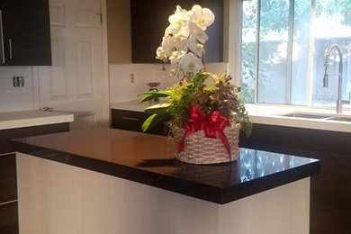 Enclosed kitchen - large modern u-shaped dark wood floor and brown floor enclosed kitchen idea in San Francisco with a double-bowl sink, flat-panel cabinets, dark wood cabinets, solid surface countertops, white backsplash, subway tile backsplash, stainless steel appliances, an island and white countertops