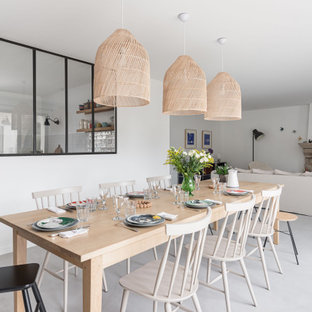 Réalisation d'une salle à manger ouverte sur la cuisine nordique de taille moyenne avec un mur blanc, une cheminée standard, un manteau de cheminée en pierre et un sol gris.