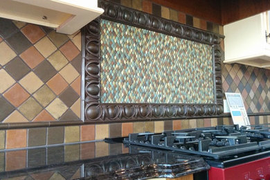 Example of a mid-sized tuscan enclosed kitchen design in Edmonton with glass-front cabinets, white cabinets, granite countertops, multicolored backsplash, terra-cotta backsplash, colored appliances and an island