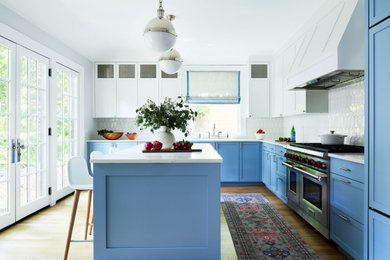Kitchen - large transitional l-shaped light wood floor kitchen idea in Boston with an undermount sink, shaker cabinets, blue cabinets, quartz countertops, white backsplash, ceramic backsplash, paneled appliances and white countertops