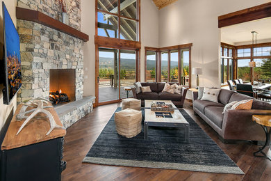 Living room - rustic open concept dark wood floor living room idea in Seattle with beige walls, a standard fireplace, a stone fireplace and a wall-mounted tv
