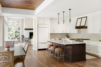 Eat-in kitchen - large transitional l-shaped medium tone wood floor eat-in kitchen idea in Minneapolis with a drop-in sink, white cabinets, quartzite countertops, green backsplash, ceramic backsplash, paneled appliances, an island and white countertops