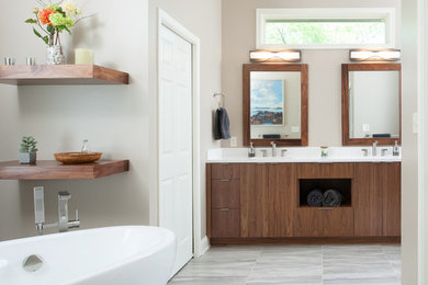 Design ideas for a large modern master bathroom in Kansas City with flat-panel cabinets, medium wood cabinets, engineered quartz benchtops, a freestanding tub, beige walls, ceramic floors, an alcove shower, ceramic tile and an integrated sink.