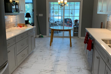 Example of a mid-sized trendy galley vinyl floor, white floor and vaulted ceiling eat-in kitchen design in Louisville with an undermount sink, flat-panel cabinets, gray cabinets, quartz countertops, gray backsplash, ceramic backsplash, stainless steel appliances, no island and white countertops