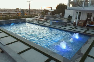 Large trendy backyard rectangular natural pool fountain photo in Orange County with decking