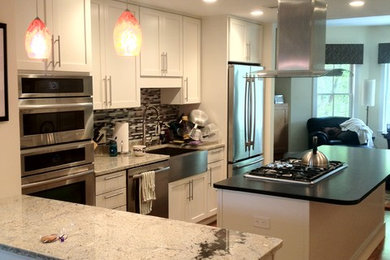 Example of a large trendy l-shaped dark wood floor, brown floor and vaulted ceiling kitchen pantry design in Boston with a farmhouse sink, recessed-panel cabinets, white cabinets, granite countertops, multicolored backsplash, matchstick tile backsplash, stainless steel appliances, an island and multicolored countertops