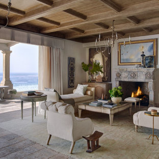 Repräsentatives, Offenes, Mittelgroßes, Fernseherloses Mediterranes Wohnzimmer mit weißer Wandfarbe, Kamin, hellem Holzboden, Kaminsims aus Stein und beigem Boden in Orange County