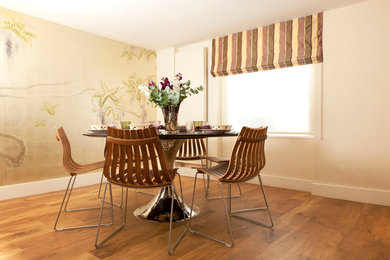 Photo of a transitional dining room in London with beige walls and medium hardwood floors.