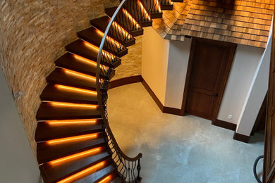 Elegant wooden curved open, wood railing and brick wall staircase photo in Chicago