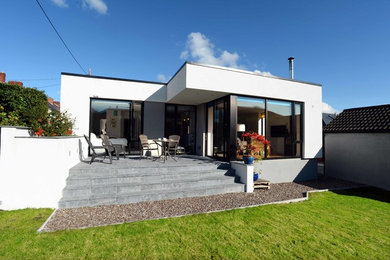 Design ideas for a mid-sized modern one-storey white house exterior in Cork with a flat roof.