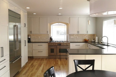 Enclosed kitchen - large transitional u-shaped light wood floor and multicolored floor enclosed kitchen idea in Denver with a double-bowl sink, shaker cabinets, white cabinets, quartz countertops, white backsplash, mosaic tile backsplash, stainless steel appliances and a peninsula