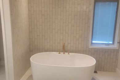 Diseño de cuarto de baño doble con bañera exenta y encimeras blancas