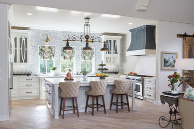 Design ideas for a large traditional u-shaped kitchen in Oklahoma City with raised-panel cabinets, white cabinets, grey splashback, stainless steel appliances, light hardwood floors and with island.