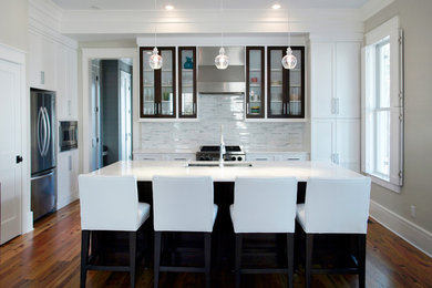 Inspiration for a contemporary dark wood floor kitchen remodel in Charleston with glass-front cabinets, white cabinets, an island, an undermount sink, granite countertops, gray backsplash, glass sheet backsplash and stainless steel appliances
