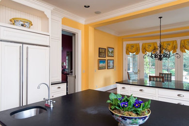 Example of a classic u-shaped medium tone wood floor and brown floor eat-in kitchen design in Nashville with beaded inset cabinets, white cabinets, granite countertops, white appliances and two islands