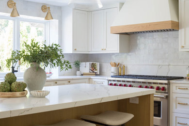 Inspiration for a large transitional u-shaped light wood floor open concept kitchen remodel in Seattle with an undermount sink, shaker cabinets, white cabinets, quartz countertops, gray backsplash, terra-cotta backsplash, stainless steel appliances, an island and white countertops