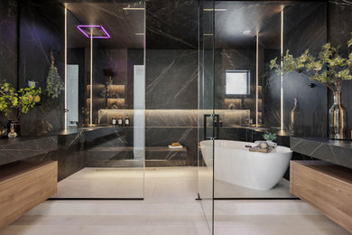 Example of a trendy black and white tile and porcelain tile double-sink bathroom design in Las Vegas with glass-front cabinets, medium tone wood cabinets, a hinged shower door and black countertops