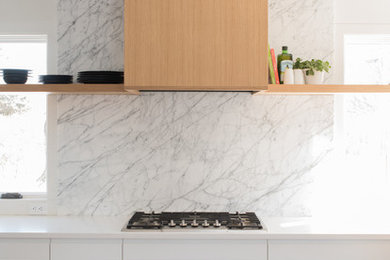 Inspiration for a small modern l-shaped medium tone wood floor and brown floor kitchen remodel in Minneapolis with an undermount sink, flat-panel cabinets, white cabinets, quartz countertops, white backsplash, marble backsplash, stainless steel appliances and white countertops