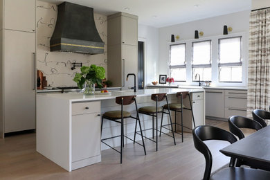 Example of a large minimalist l-shaped light wood floor eat-in kitchen design in Birmingham with a farmhouse sink, shaker cabinets, quartz countertops, paneled appliances, an island and white countertops