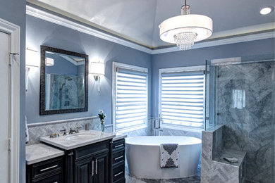 Inspiration for a large transitional master bathroom in Houston with furniture-like cabinets, grey cabinets, a freestanding tub, a curbless shower, a two-piece toilet, gray tile, stone tile, blue walls, marble floors, an undermount sink and marble benchtops.