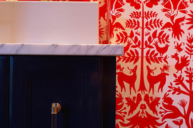 Small arts and crafts concrete floor, brown floor and wallpaper powder room photo in Austin with shaker cabinets, blue cabinets, red walls, a vessel sink, marble countertops, gray countertops and a built-in vanity