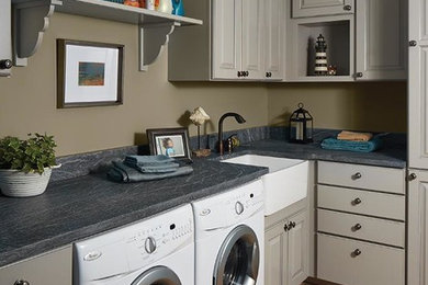 Dedicated laundry room - mid-sized transitional l-shaped medium tone wood floor and brown floor dedicated laundry room idea in Orange County with a farmhouse sink, raised-panel cabinets, gray cabinets, soapstone countertops, beige walls, a side-by-side washer/dryer and gray countertops