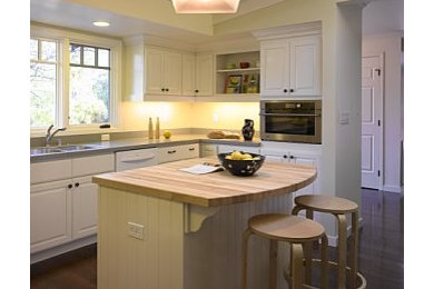 Large elegant u-shaped dark wood floor, brown floor and exposed beam kitchen photo in San Francisco with a double-bowl sink, raised-panel cabinets, white cabinets, wood countertops, stainless steel appliances, an island and beige countertops