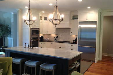 Inspiration for a mid-sized timeless single-wall medium tone wood floor eat-in kitchen remodel in Atlanta with a farmhouse sink, shaker cabinets, white cabinets, marble countertops, white backsplash, subway tile backsplash, stainless steel appliances and an island