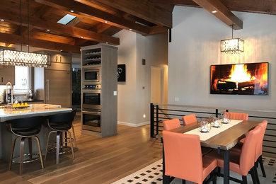 Example of a mid-sized mid-century modern u-shaped medium tone wood floor open concept kitchen design in Boise with a single-bowl sink, flat-panel cabinets, gray cabinets, granite countertops, blue backsplash, glass tile backsplash, paneled appliances and an island