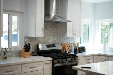 Large minimalist l-shaped vinyl floor and brown floor eat-in kitchen photo in Los Angeles with an undermount sink, shaker cabinets, white cabinets, quartz countertops, multicolored backsplash, subway tile backsplash, stainless steel appliances, an island and white countertops