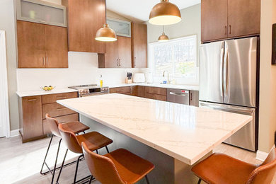 Eat-in kitchen - mid-sized gray floor and vaulted ceiling eat-in kitchen idea in Philadelphia with flat-panel cabinets, medium tone wood cabinets, quartzite countertops, white backsplash, ceramic backsplash, stainless steel appliances, an island and white countertops