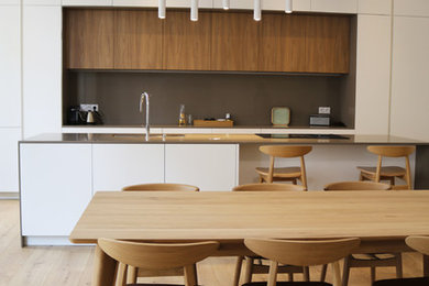 Aménagement d'une très grande cuisine américaine parallèle et encastrable contemporaine avec un évier encastré, un placard à porte affleurante, des portes de placard blanches, un plan de travail en quartz modifié, une crédence marron, parquet clair, îlot, un sol marron et un plan de travail marron.