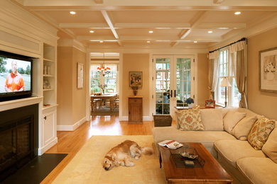 Mid-sized elegant open concept medium tone wood floor and brown floor family room photo in Baltimore with beige walls, a standard fireplace and a concealed tv