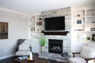 Living room - mid-sized traditional enclosed light wood floor living room idea in Other with beige walls, a standard fireplace, a stone fireplace and a wall-mounted tv
