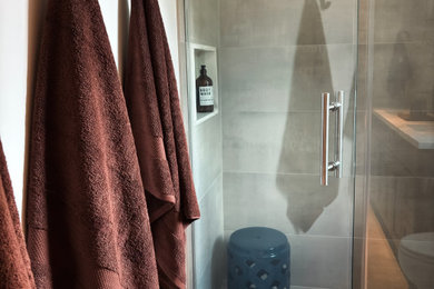 This is an example of a medium sized modern family bathroom in Other with shaker cabinets, blue cabinets, a built-in shower, a one-piece toilet, grey tiles, porcelain tiles, white walls, porcelain flooring, a built-in sink, quartz worktops, grey floors, a hinged door, blue worktops, double sinks and a freestanding vanity unit.