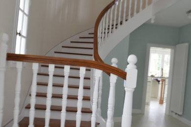 Aménagement d'un escalier peint courbe avec des marches en bois peint et un garde-corps en bois.