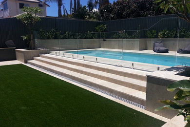 Inspiration for a contemporary backyard full sun garden in Perth with a retaining wall and natural stone pavers.