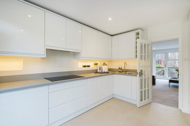 Mid-sized minimalist l-shaped kitchen photo in London with a drop-in sink, stainless steel countertops, stainless steel appliances and no island