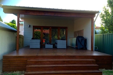 Inspiration for a large tropical backyard deck in Sydney with an outdoor kitchen and a roof extension.
