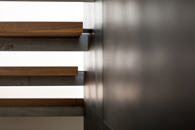 Diseño de escalera en U contemporánea sin contrahuella con escalones de madera y barandilla de varios materiales