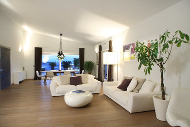 Large contemporary open concept living room in Other with white walls and light hardwood floors.