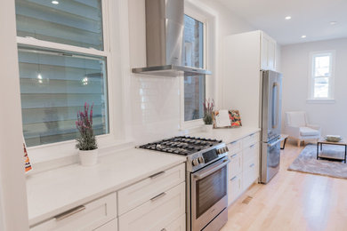 Example of a large trendy galley light wood floor and yellow floor eat-in kitchen design in Chicago with a single-bowl sink, shaker cabinets, white cabinets, quartzite countertops, white backsplash, ceramic backsplash, stainless steel appliances, an island and white countertops