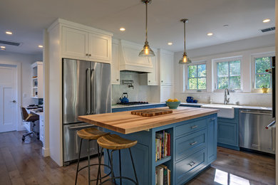 Photo of a mid-sized country u-shaped separate kitchen in San Francisco with a farmhouse sink, shaker cabinets, turquoise cabinets, quartz benchtops, stainless steel appliances, light hardwood floors, with island, white splashback, marble splashback and brown floor.