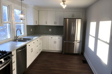Enclosed kitchen - mid-sized traditional l-shaped dark wood floor and brown floor enclosed kitchen idea in Other with a drop-in sink, recessed-panel cabinets, white cabinets, laminate countertops, green backsplash, ceramic backsplash, stainless steel appliances, no island and gray countertops