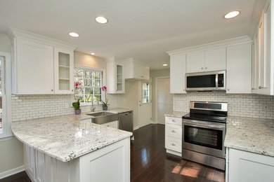 Eat-in kitchen - mid-sized transitional l-shaped dark wood floor eat-in kitchen idea in Raleigh with a farmhouse sink, shaker cabinets, white cabinets, granite countertops, white backsplash, ceramic backsplash, stainless steel appliances and an island