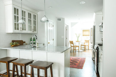 Example of a large eclectic l-shaped dark wood floor eat-in kitchen design in Boston with an undermount sink, shaker cabinets, white cabinets, quartzite countertops, white backsplash, subway tile backsplash, stainless steel appliances and a peninsula