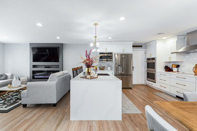 Example of a mid-sized classic u-shaped light wood floor and brown floor eat-in kitchen design in New York with an undermount sink, shaker cabinets, white cabinets, quartz countertops, gray backsplash, marble backsplash, stainless steel appliances, a peninsula and white countertops