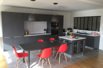 This is an example of a large modern galley open plan kitchen in Paris with a double-bowl sink, flat-panel cabinets, grey cabinets, quartz benchtops, white splashback, panelled appliances, ceramic floors, with island and grey floor.