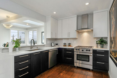 Photo of a mid-sized contemporary u-shaped separate kitchen in San Francisco with a single-bowl sink, flat-panel cabinets, black cabinets, white splashback, stainless steel appliances, dark hardwood floors and no island.