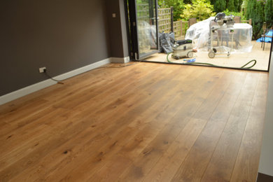 Photo of a contemporary living room in Surrey with medium hardwood flooring and brown floors.